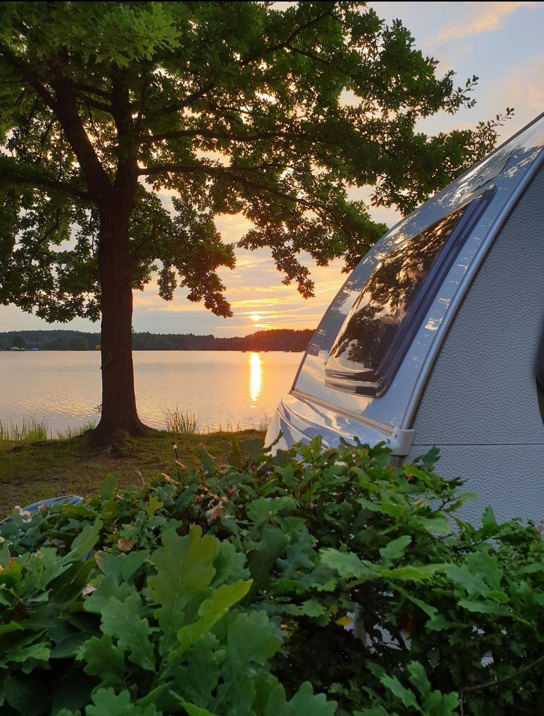 Wohnwagenheck bei Sonnenuntergang mit Blick auf den See - Camping in Bayern